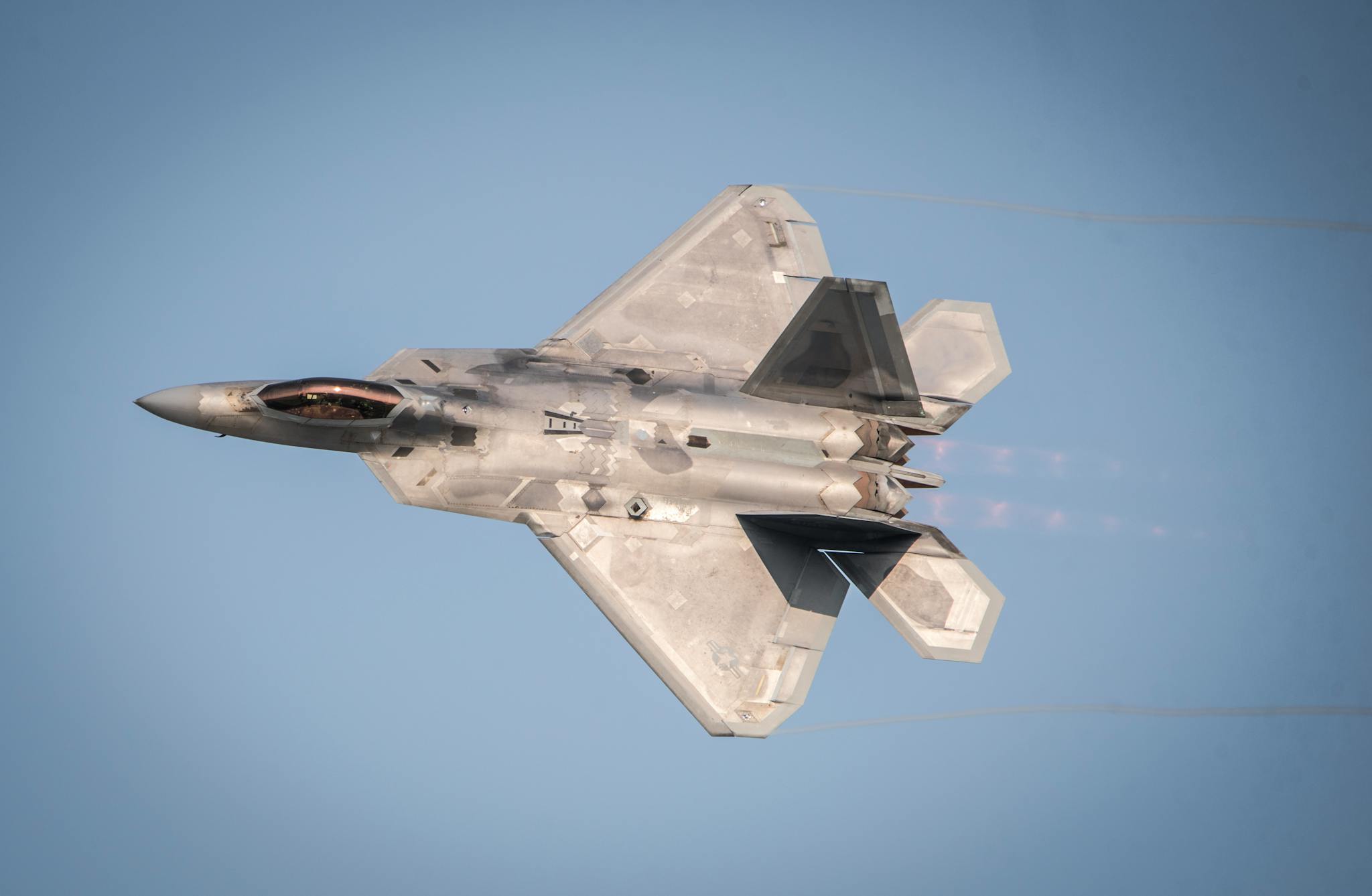 High-speed fighter jet flying during daylight, showing aerodynamic design against a blue sky.