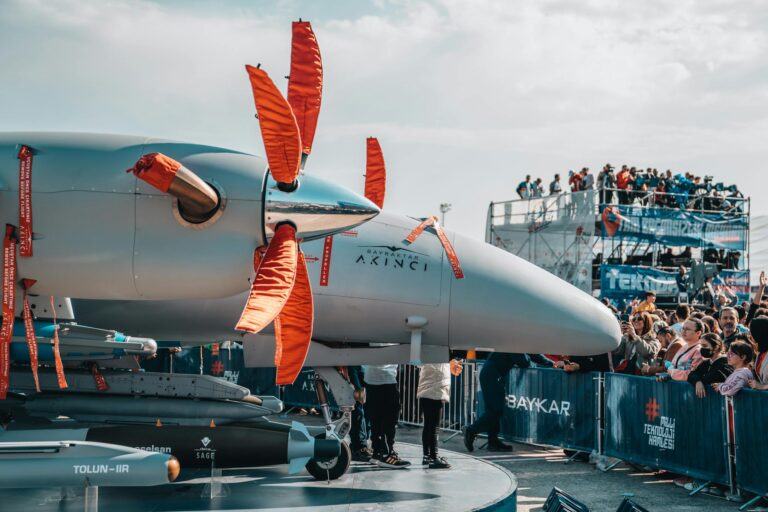 Military drone on display with large crowds at an airshow, showcasing aviation technology.